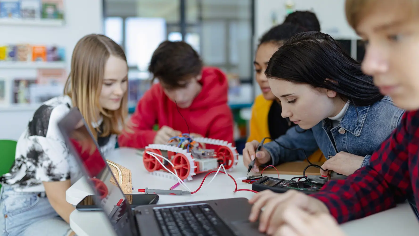 Schülergruppe beim Programmieren von elektrischen Minifahrzeugen