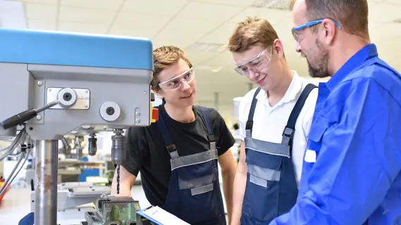 Nicht immer läuft es in der Ausbildung rund - die wichtigsten Schritte, wenn nur ein Wechsel hilft (im Bild: Ausbilder mit zwei Auszubildenden an einer Maschine in der Werkhalle).