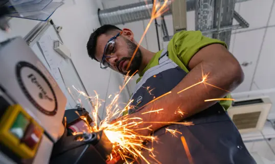 IndustriemechanikerInnen erlernen vielseitige Tätigkeiten und haben zahlreiche Aufstiegsmöglichkeiten - im Bild: Auszubildender an einer Maschine.