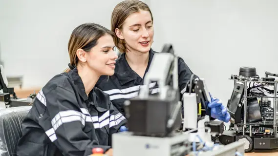 Zwei weibliche Nachwuchskräfte bei technischen Arbeiten in der Fabrik.